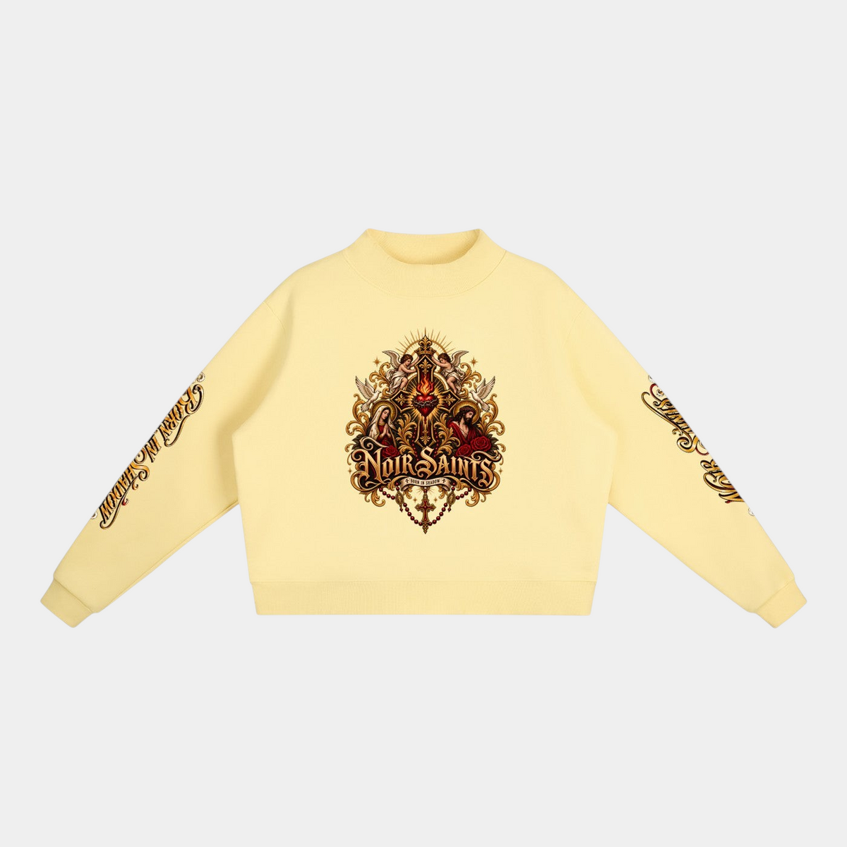 NOIR SAINTS Canada cropped mock-neck fleece sweatshirt in pale yellow with ornate sacred heart graphic and sleeve text.